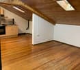 wooden floors, vaulted ceiling, skylights, kitchen area with cabinet and sink, black oven