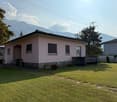 single-family house, pink facade, tiled roof, well-kept garden, mountains in the background