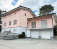 Two-story house, pink and gray exterior, white doors, two garages, balcony, white fence