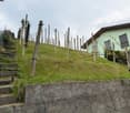 House on a hill, wooden fence, wooden stairs, green grass, concrete wall