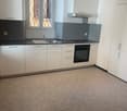 modern kitchen, white cabinets, black countertops, stainless steel sink, oven, extractor hood, electrical outlets, tiled floor