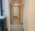 arched hallway, white walls, gray floor, open door, wooden floor in the room, black fireplace, white radiator