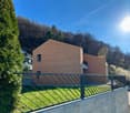Modern house with brick facade, large windows, balcony, located on a slope with a view of the mountains