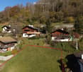 plot of land with several chalets on a hillside, surrounded by greenery