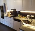 modern kitchen with granite countertop, black induction stove, stainless steel sink, dishwasher, oven, black and white cabinets, granite flooring