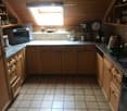 Kitchen with tiled floor, wooden cabinets, granite countertop, oven, microwave, sink, and kitchen appliances