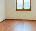 hardwood floor, a single window with wooden window frame and white curtains, a power outlet