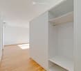 An empty room with a white wardrobe and wooden floor