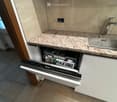 dishwasher under marble countertop, silver sink, wooden door, tiled floor