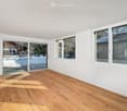 wooden floor, white walls, sliding glass doors to balcony, three large windows