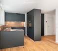 Modern kitchen with a wooden countertop, built-in oven, built-in dishwasher, under cabinet lighting, sleek cabinets, and an island sink with faucet