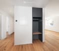 Minimalist room with built-in wardrobe, wooden floors, white walls, and an empty shelf inside the wardrobe