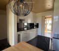 White cabinets, black countertops, hanging lamp, stainless steel sink, faucet, black chair, wooden table
