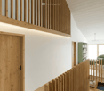 wooden door, wooden railing, white walls, wooden ceiling, wooden floor, green bookshelf, white chair, white sofa