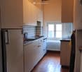 kitchen with white cabinets, tiled floor, refrigerator, sink, oven, window, radiator
