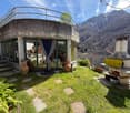 Curved concrete house, large windows, balcony, garden, mountain view