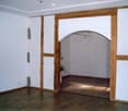 empty room, wooden floor, white walls, wooden arch, plant in corner