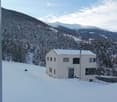 House. Modern white house on a snowy mountain slope with a clear view of the mountains.