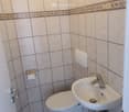 Bathroom. Small bathroom with white tiles, a toilet, a sink, and a wall-mounted soap dispenser.