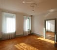 Empty room with parquet floors, white walls, white curtains, glass windows, radiator, ceiling lamp