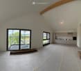 Furnished Room. Open-plan space with exposed wooden beams, large windows, and a fitted kitchen area with cabinets and an oven. The floor is covered with protective sheeting.