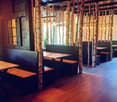 Restaurant interior with wooden tables, benches, and hanging lamps, featuring birch tree trunks as decorative columns.