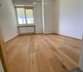 Empty room with wooden flooring, white walls, and a window with blinds. No furniture or equipment is present.