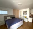 Modern bedroom with a large bed, nightstands, a painting, and a round ceiling light.