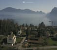 Aerial view of a residential area with houses, mountains, and a lake in the background.