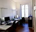 Office space with two desks, multiple computer monitors, keyboards, mice, chairs, a filing cabinet, and various office supplies.