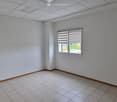 Empty room with white walls, tiled floor, and a single window with blinds.