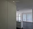 Empty room with modern design, white cabinetry, large windows with blinds, and a dark tiled floor.