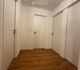 Empty hallway with wooden flooring, white walls, and two closed doors.