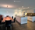 Modern kitchen with white cabinets, a central island, a dining table with chairs, and various appliances.