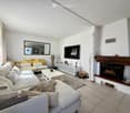Modern living room with a large sectional sofa, coffee table, fireplace, TV, and decorative items.