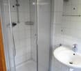 Modern bathroom with a glass-enclosed shower stall, a white sink with a chrome faucet, and a mirror above the sink.