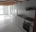 Modern kitchen with grey cabinets, stainless steel appliances, and a tiled backsplash. Features a sink, oven, dishwasher, and range hood.