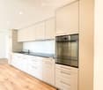 kitchen, white cabinets, wooden floor, modern appliances, glass wall