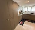 Modern kitchen with light-colored cabinets, stainless steel appliances, and a light wooden floor. The kitchen features a coffee maker, sink, and various small appliances on the counter.