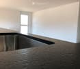 large stainless steel sink, granite countertop, white walls, large windows