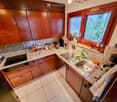 The kitchen features wooden cabinets, a granite countertop, and stainless steel appliances including a sink and oven. Various kitchen items and utensils are placed on the counter.