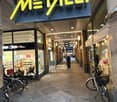 Shop entrance, signboard, bicycles parked, pathway, shop windows, people walking