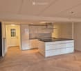modern kitchen, white cabinets, black countertop, island, wooden floor, white walls, ceiling lights, exhaust hood, sink, faucet