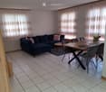Living and dining area with a dark blue sectional sofa, pink cushions, a small coffee table, a modern dining table with chairs, and a potted plant near the window.