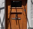Wooden door with a small window and decorative metal handle, set in a white textured wall.