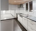 Modern kitchen with white cabinets, stainless steel appliances, and a black countertop. Features include a sink, faucet, oven, dishwasher, and a range hood.
