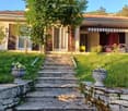 Two-story house with a tiled roof, large windows, and a covered porch area with outdoor furniture.