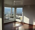 Empty room with wooden flooring, large windows offering a scenic view, and white walls.