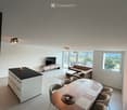 Open-plan living and dining area with a sofa, coffee table, dining table with chairs, and a kitchen island.
