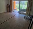 Empty room with tiled floor, large sliding glass door leading to outdoor area, and some stacked boxes in the corner.